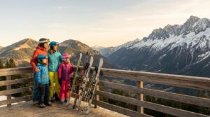 Famille souriante sur une terrasse de montagne contemplant deux massifs montagneux